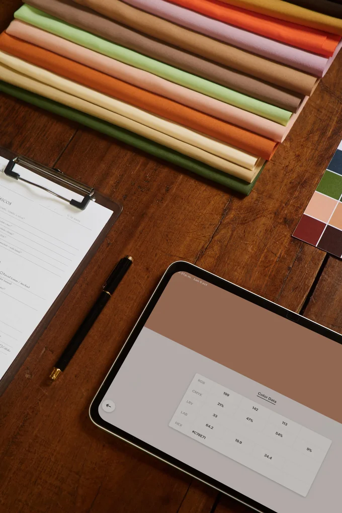 Telas, ficha y tablet con los valores de color sobre la mesa de trabajo